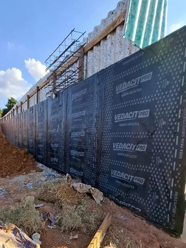 Proteção de muro de arrimo — Impermeabilização externa para bloquear a umidade do solo.