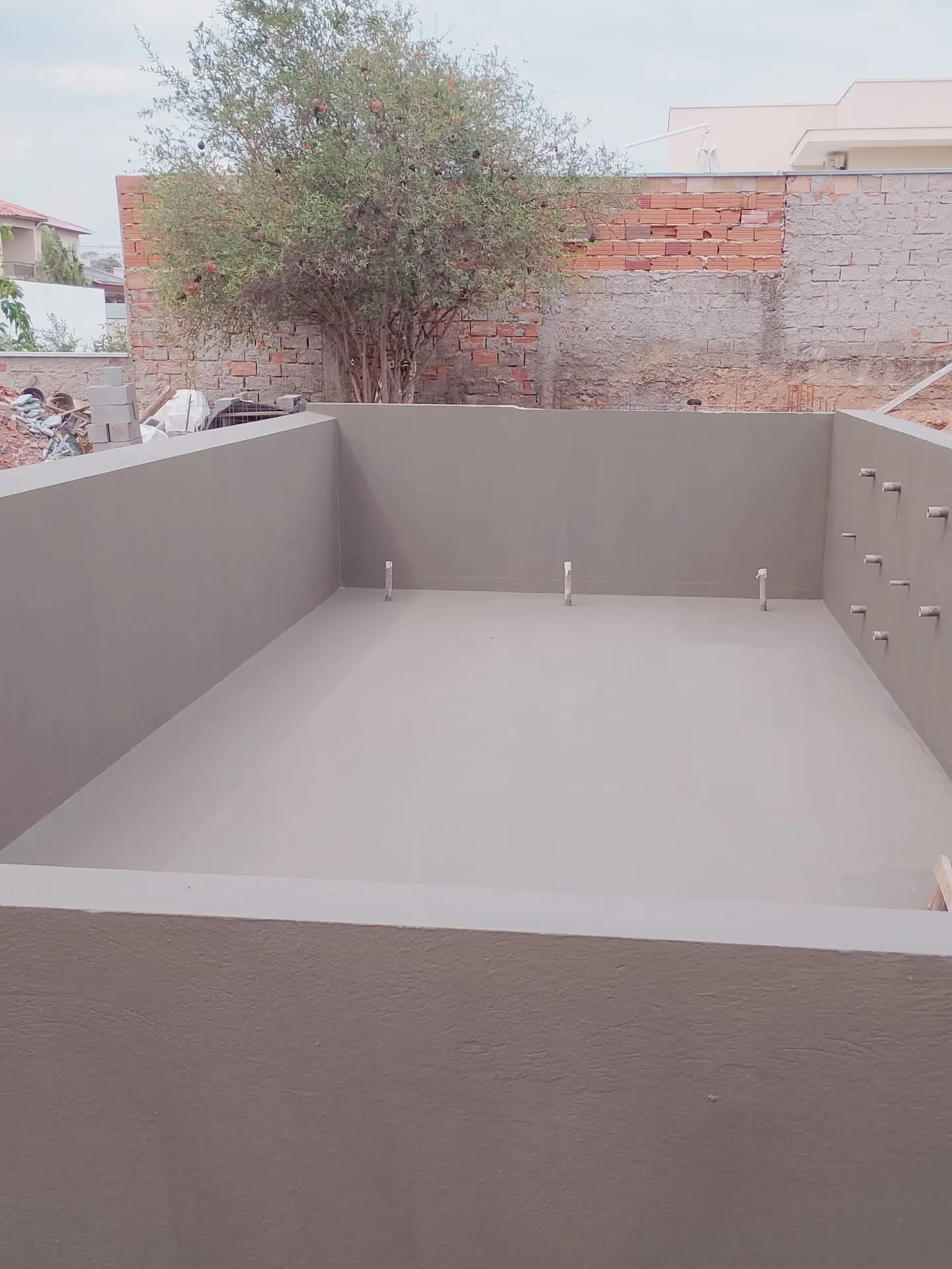 Piscina residencial em execução — Impermeabilização uniforme antes da etapa de revestimento.
